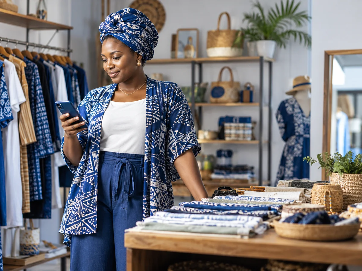 Nigerian business owner checking her phone in a clothing shop